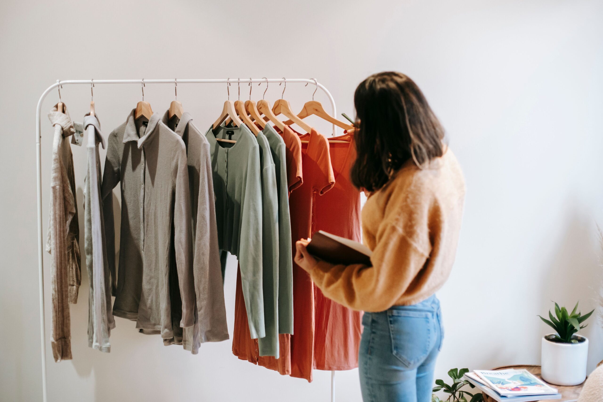Femme choisissant des vêtements sur un portant tout en prenant des notes