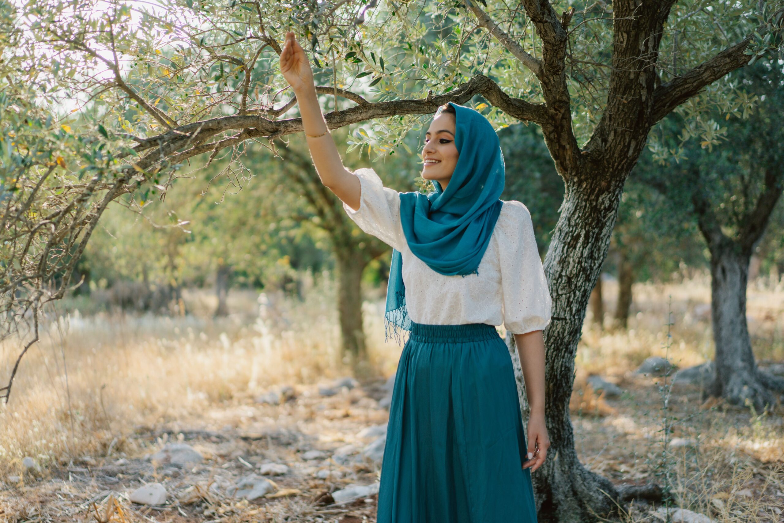 Femme portant un ensemble jupe longue bleue et haut ample blanc avec hijab dans un cadre naturel