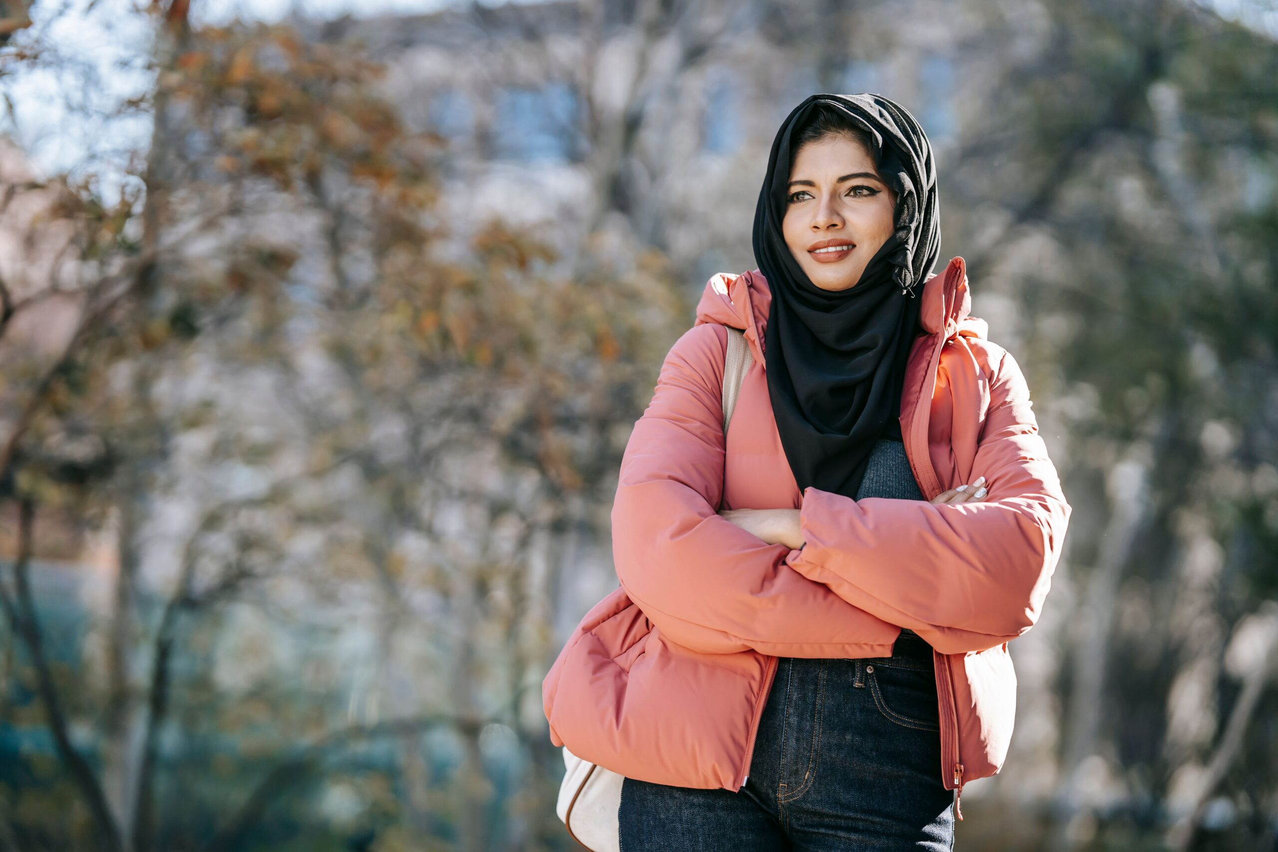 Femme portant un hijab noir et une doudoune rose dans un parc en hiver