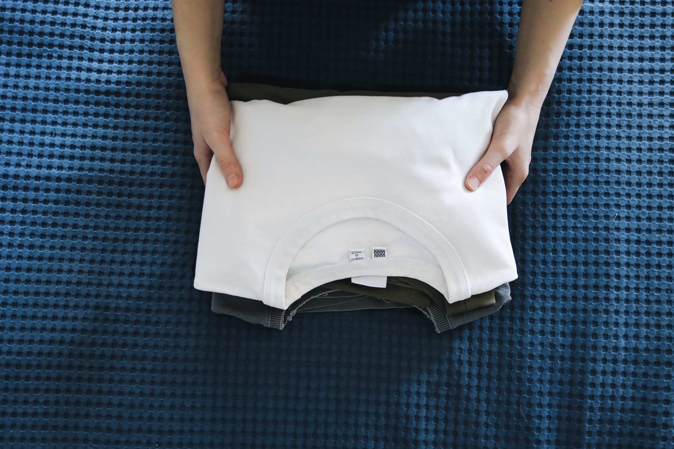 Mains pliant avec soin un vêtement blanc sur un tissu bleu