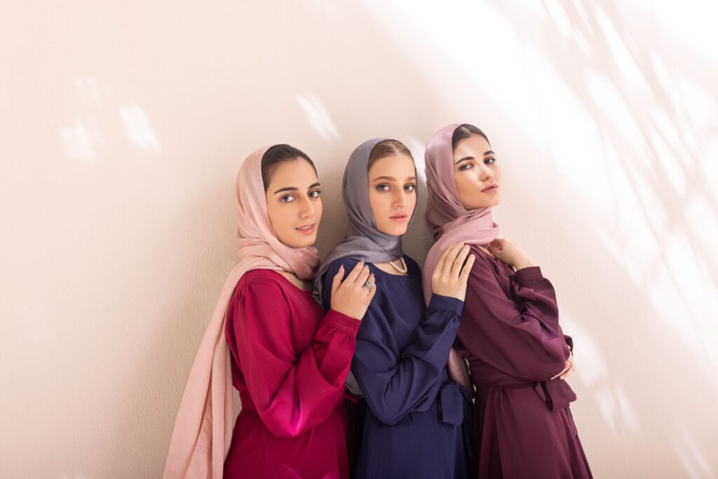 Trois femmes portant des ensembles mastour élégants dans des tons bordeaux, bleu marine et prune avec hijabs assortis