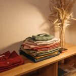 Vêtements soigneusement pliés et empilés sur une étagère en bois sous une lumière douce