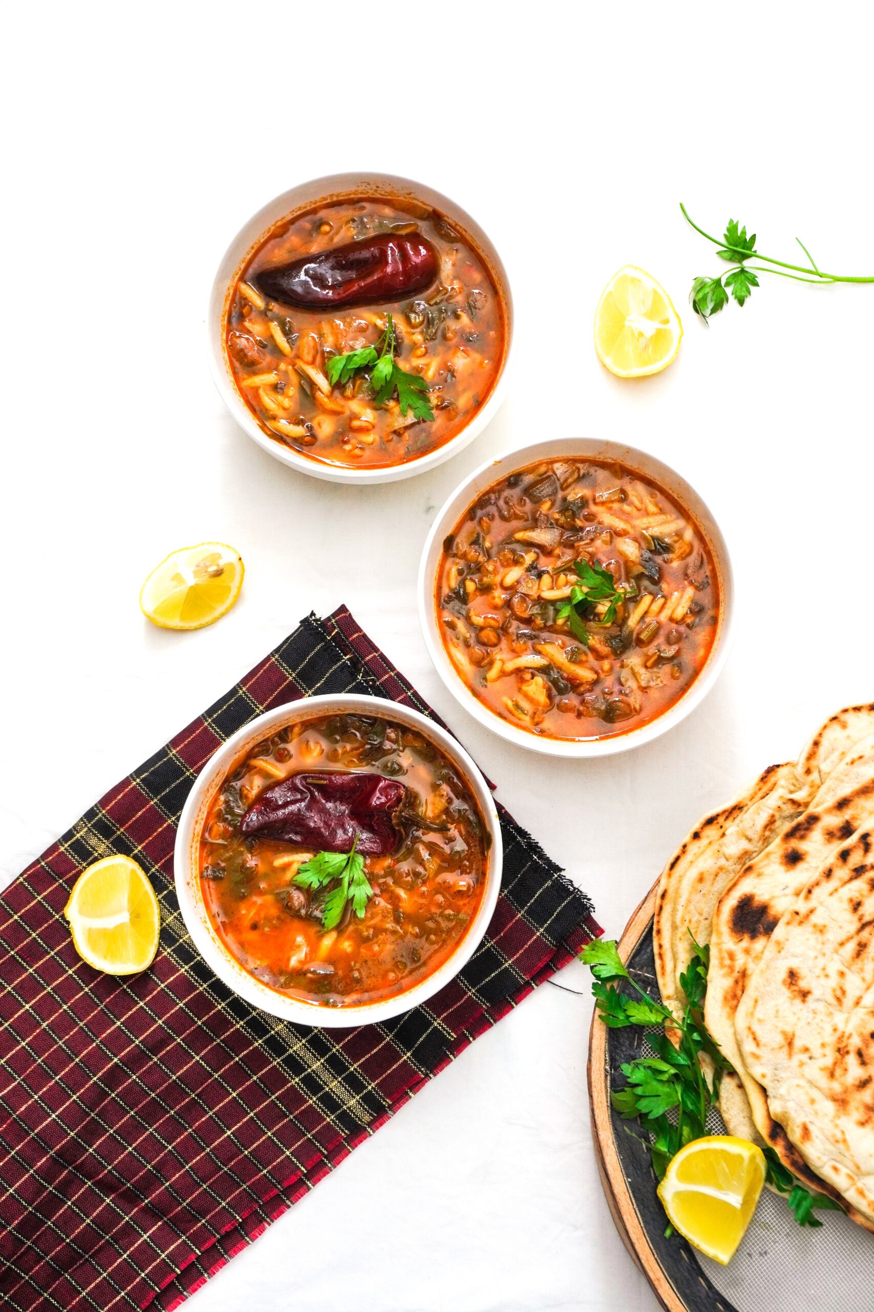 Bowls of traditional Moroccan harira soup with fresh herbs, lemon and flatbread for Ramadan
