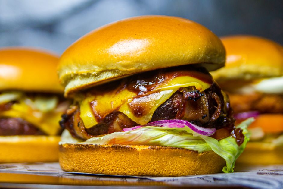 Burger gourmet avec fromage cheddar fondu, oignons caramélisés et bacon sur pain brioché