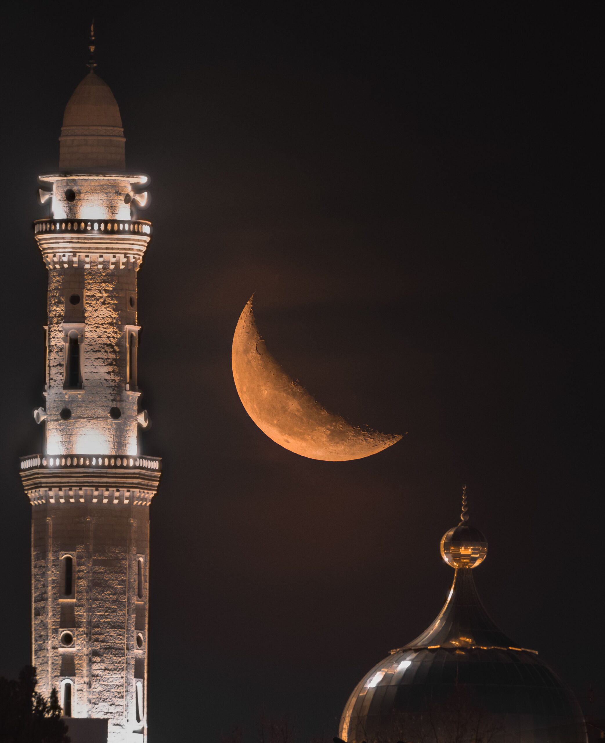 Croissant de lune doré au-dessus d'un minaret illuminé dans la nuit
