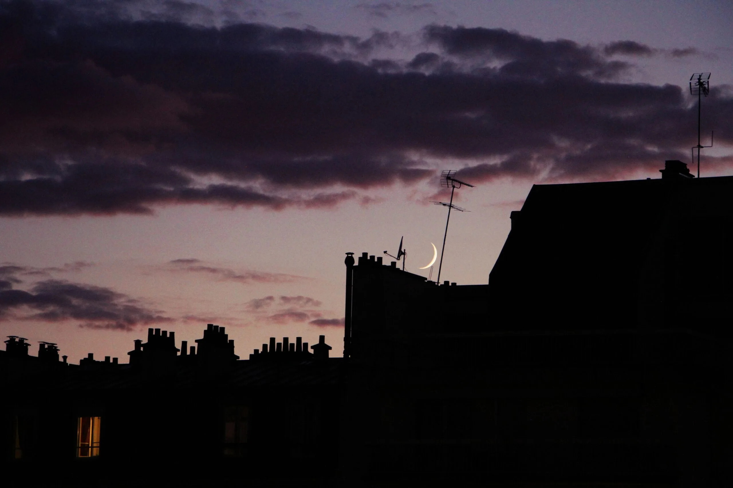 Croissant de lune visible au crépuscule au-dessus des toits d'une ville française