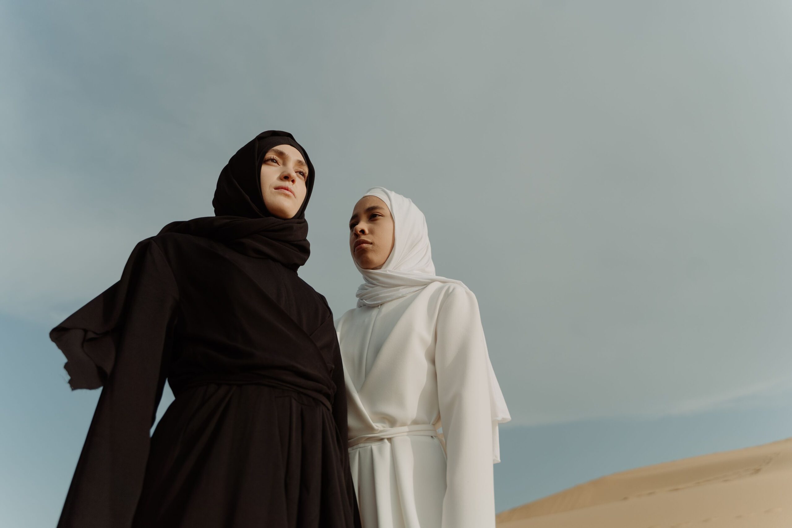 Deux femmes portant des abayas élégantes noir et blanc dans un paysage désertique