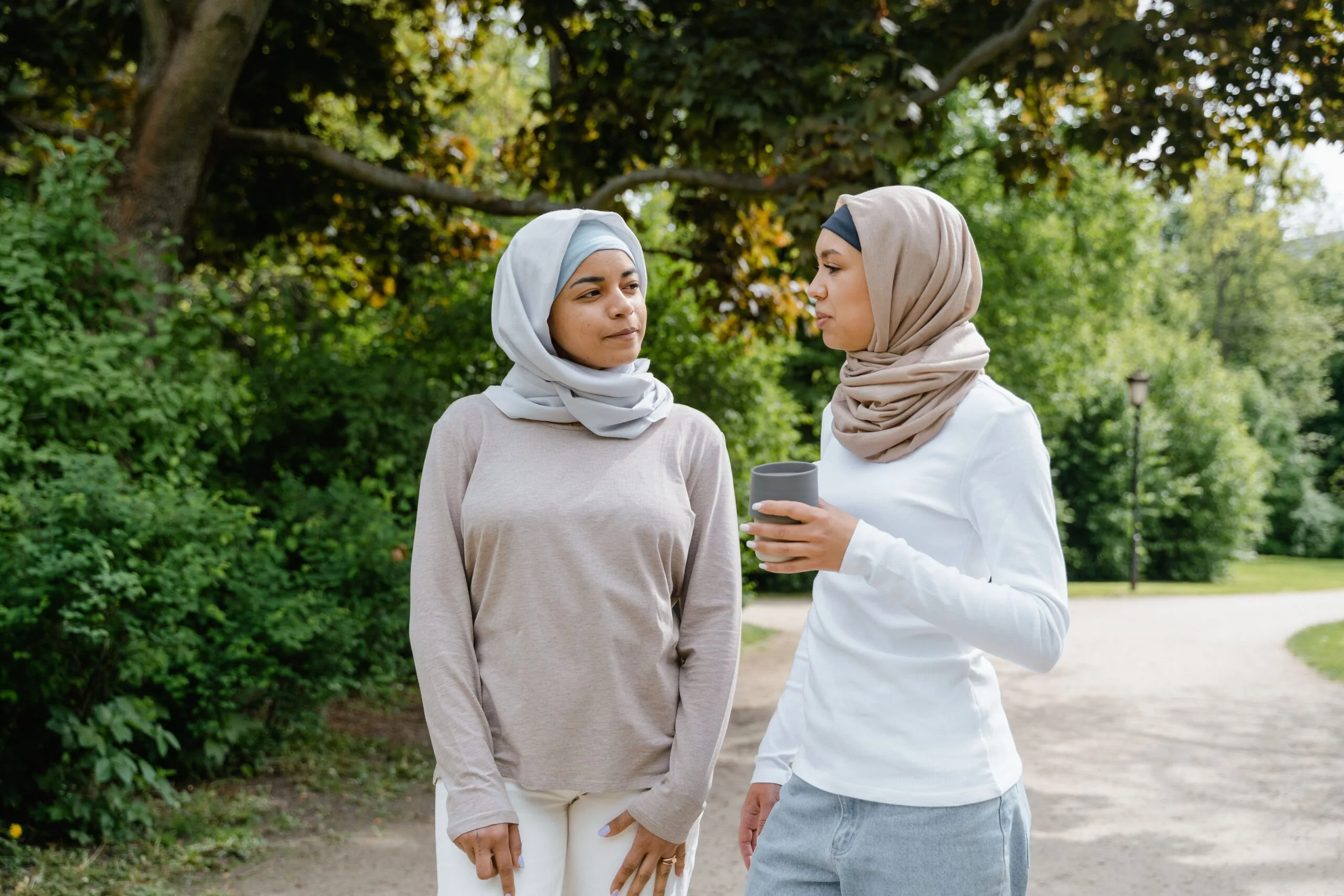 Deux femmes portant le hijab conversant amicalement dans un parc verdoyant