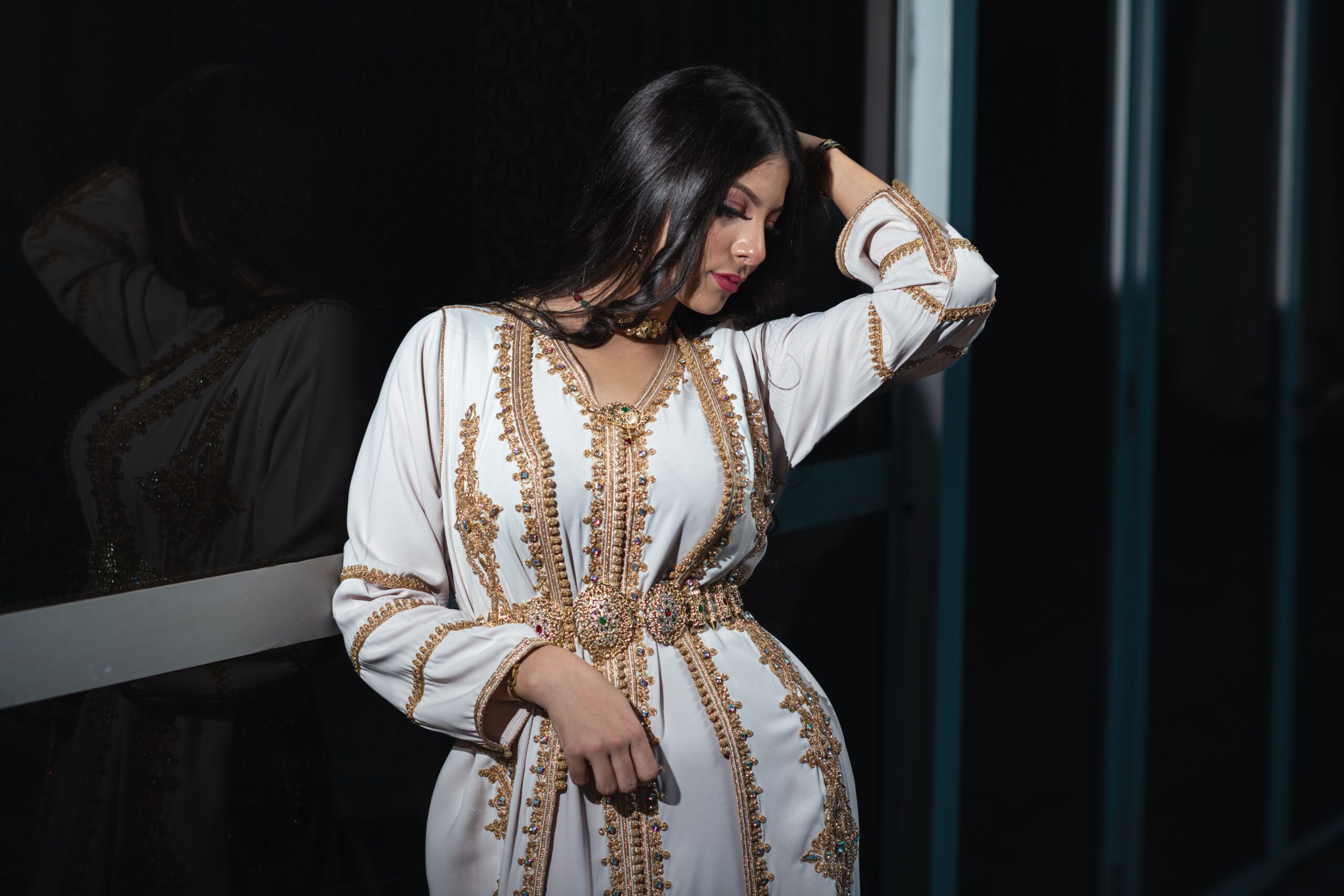 Femme en caftan blanc luxueux avec broderies dorées et ceinture ornée