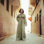 Femme portant un caftan marocain vert brodé dans une ruelle traditionnelle