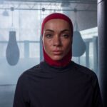 Femme portant un hijab rouge dans une salle de boxe avec des sacs de frappe