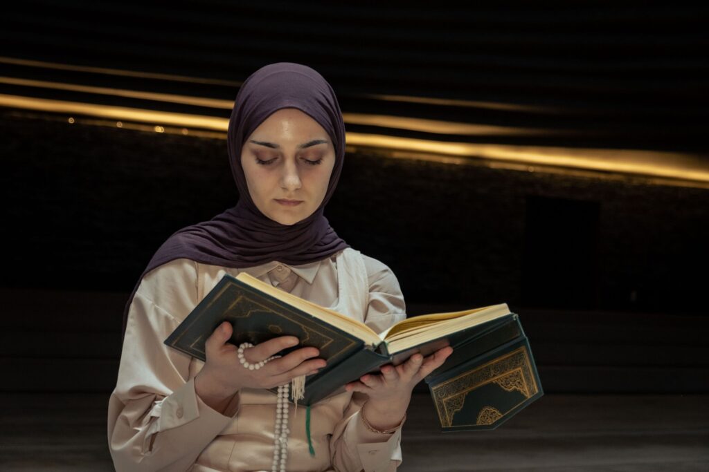 Woman wearing a hijab holding a prayer book in an atmosphere of reflection