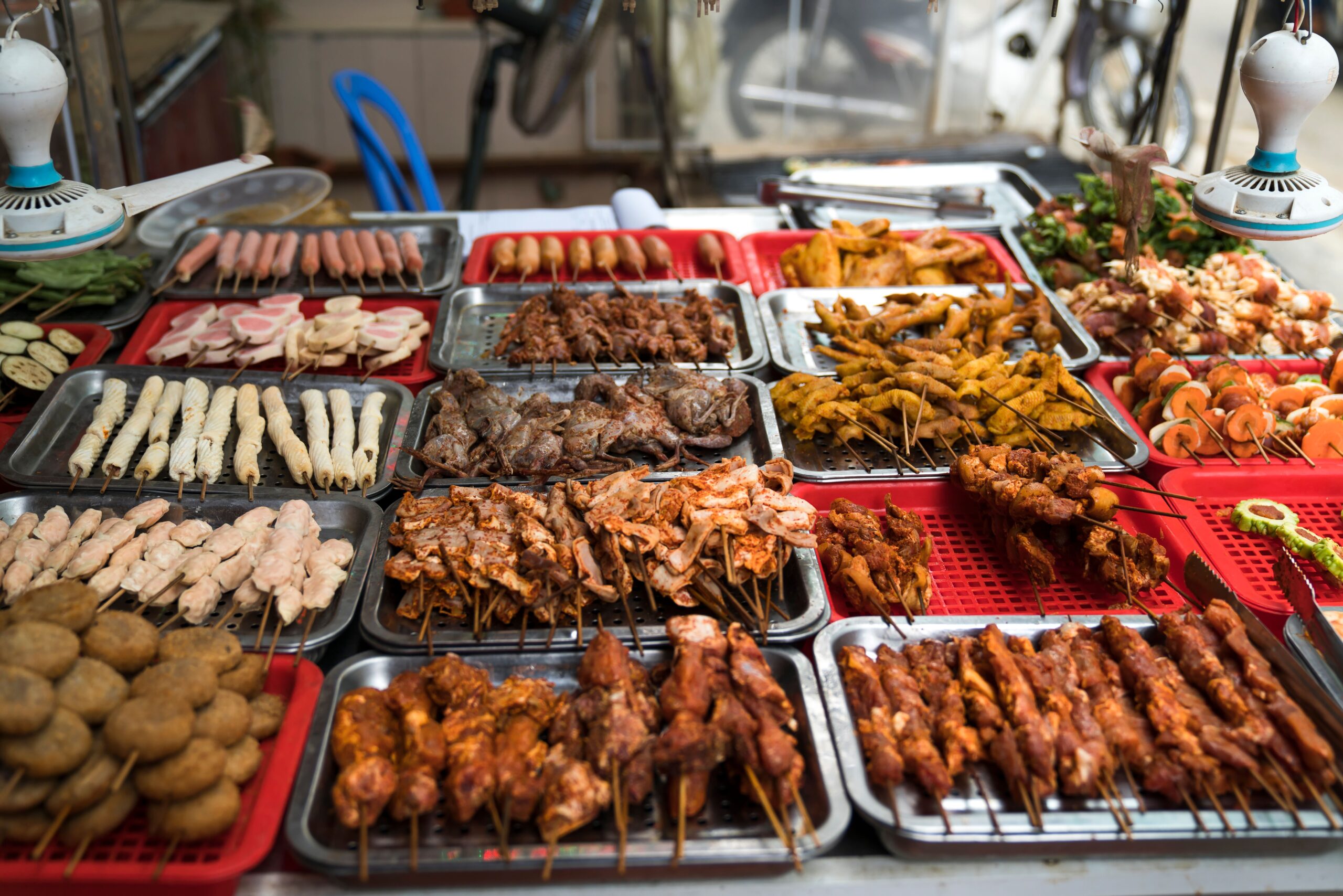 Grand buffet de street food avec brochettes de viandes grillées variées, légumes et plats chauds exposés