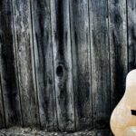 Guitare acoustique en bois posée contre un mur rustique