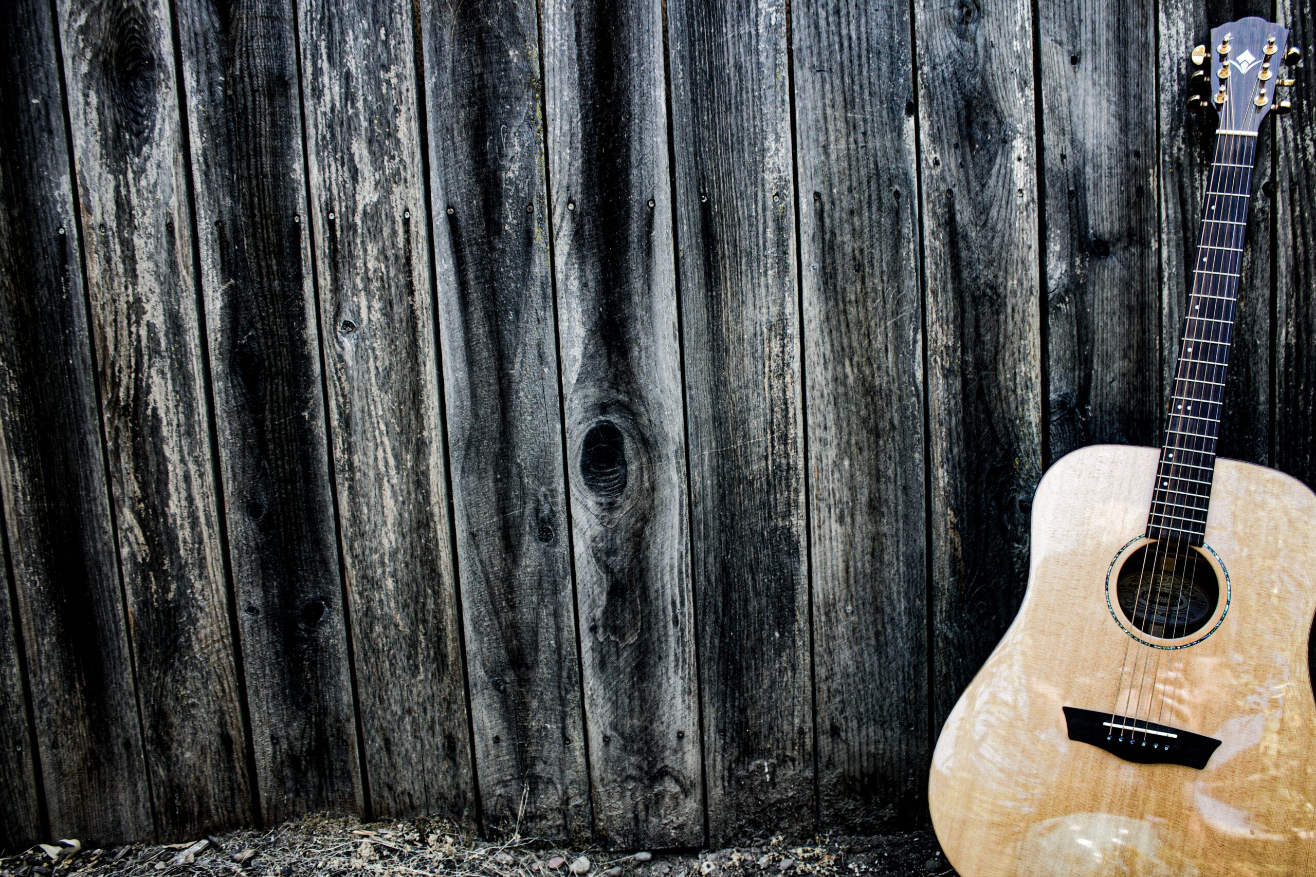 Guitare acoustique en bois posée contre un mur rustique