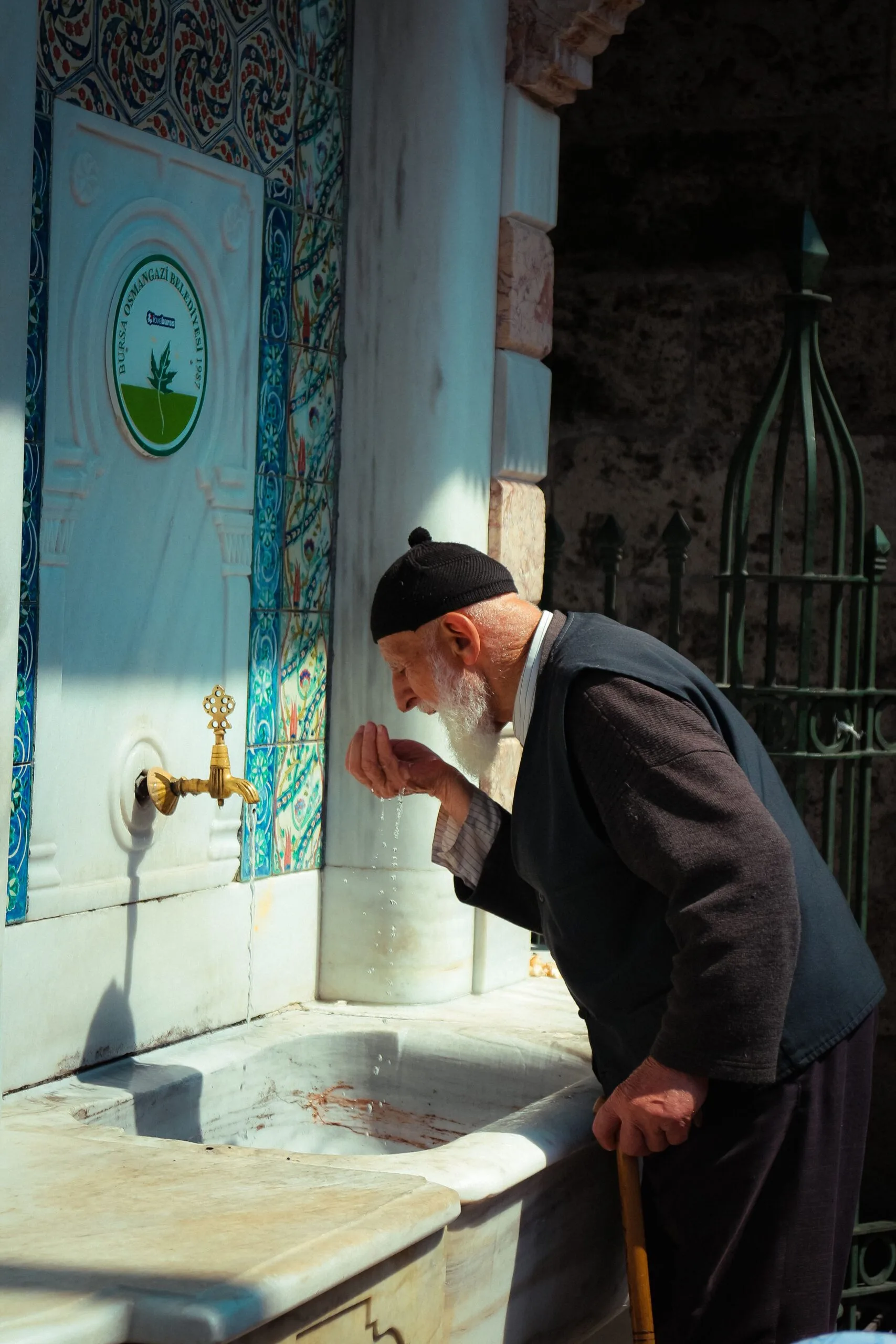 Homme effectuant ses ablutions à une fontaine de mosquée traditionnelle