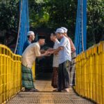 Hommes en tenue traditionnelle musulmane se saluant chaleureusement sur un pont