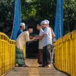 Hommes en tenue traditionnelle musulmane se saluant chaleureusement sur un pont
