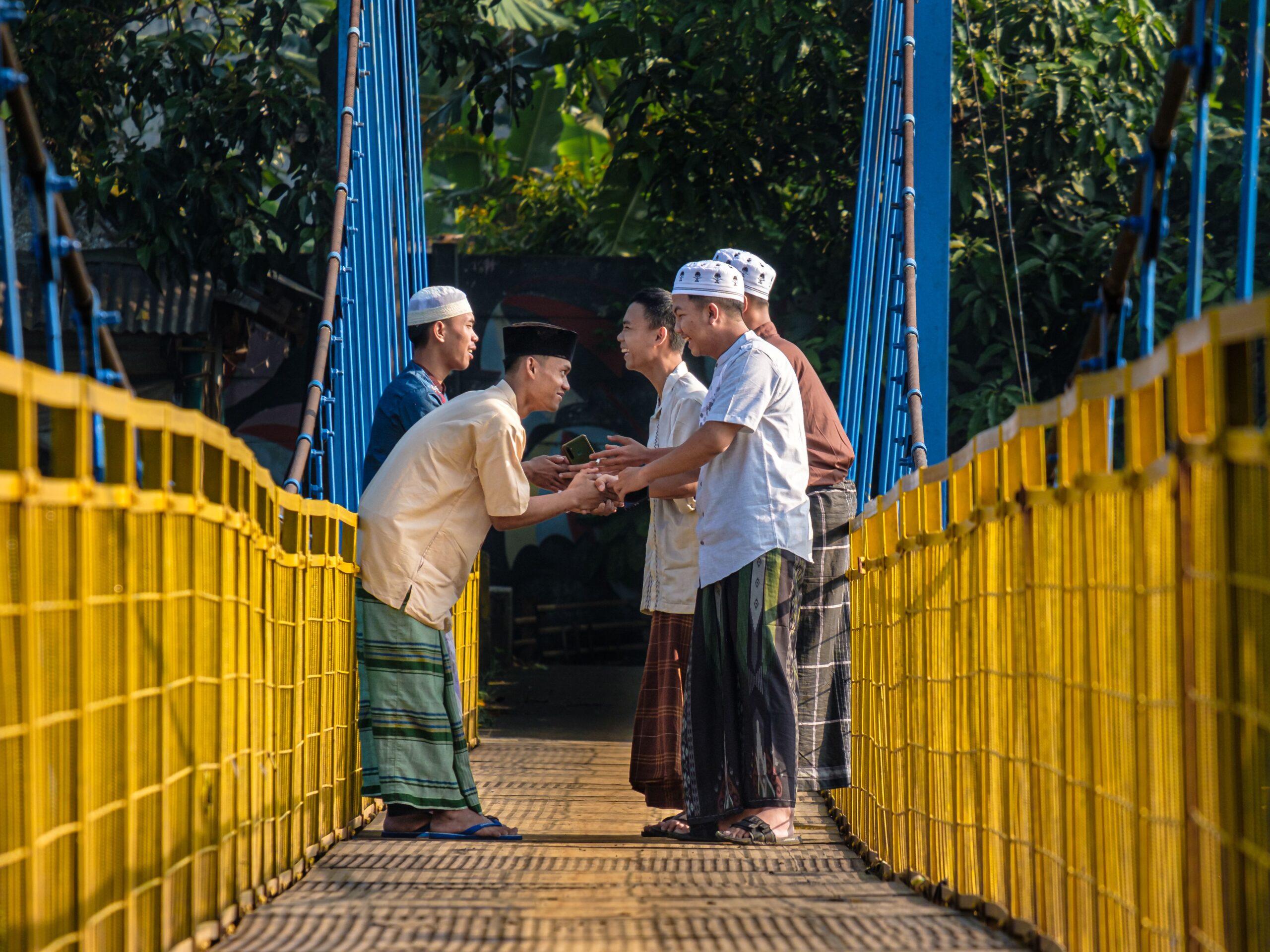 Hommes en tenue traditionnelle musulmane se saluant chaleureusement sur un pont