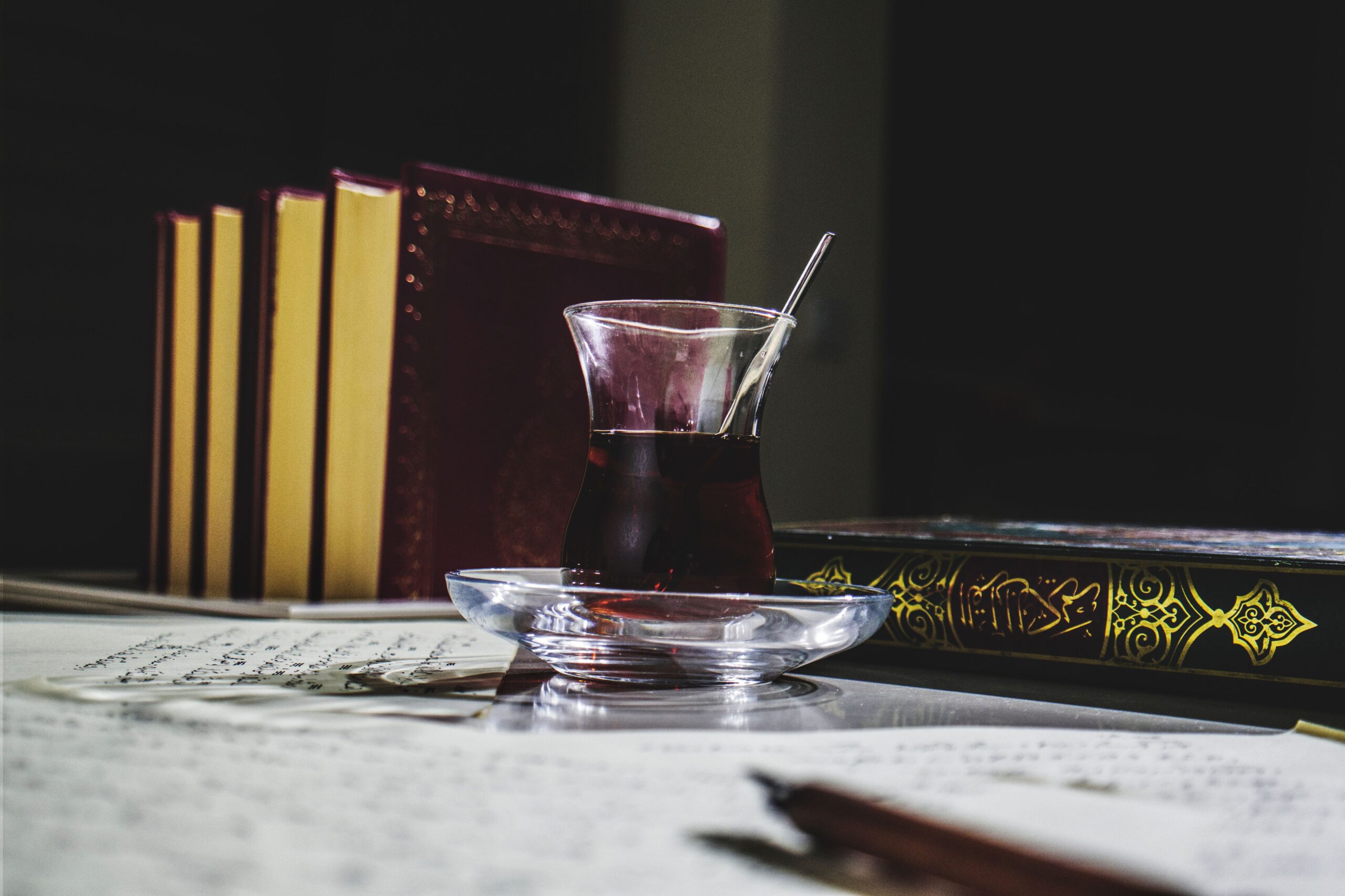 Livres religieux islamiques avec verre de thé sur une table, ambiance d'étude et de réflexion