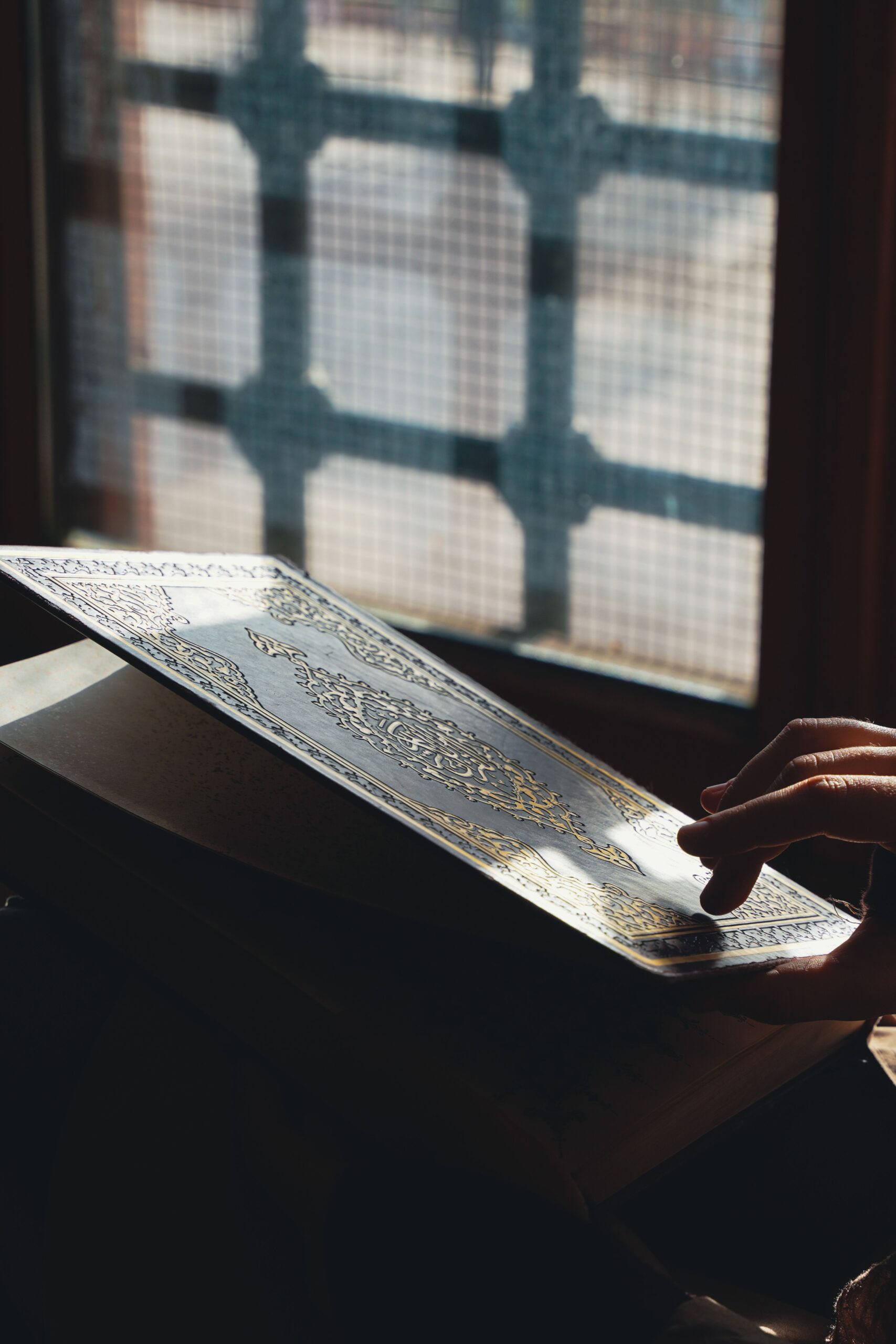 Main tenant le Coran près d'une fenêtre de mosquée