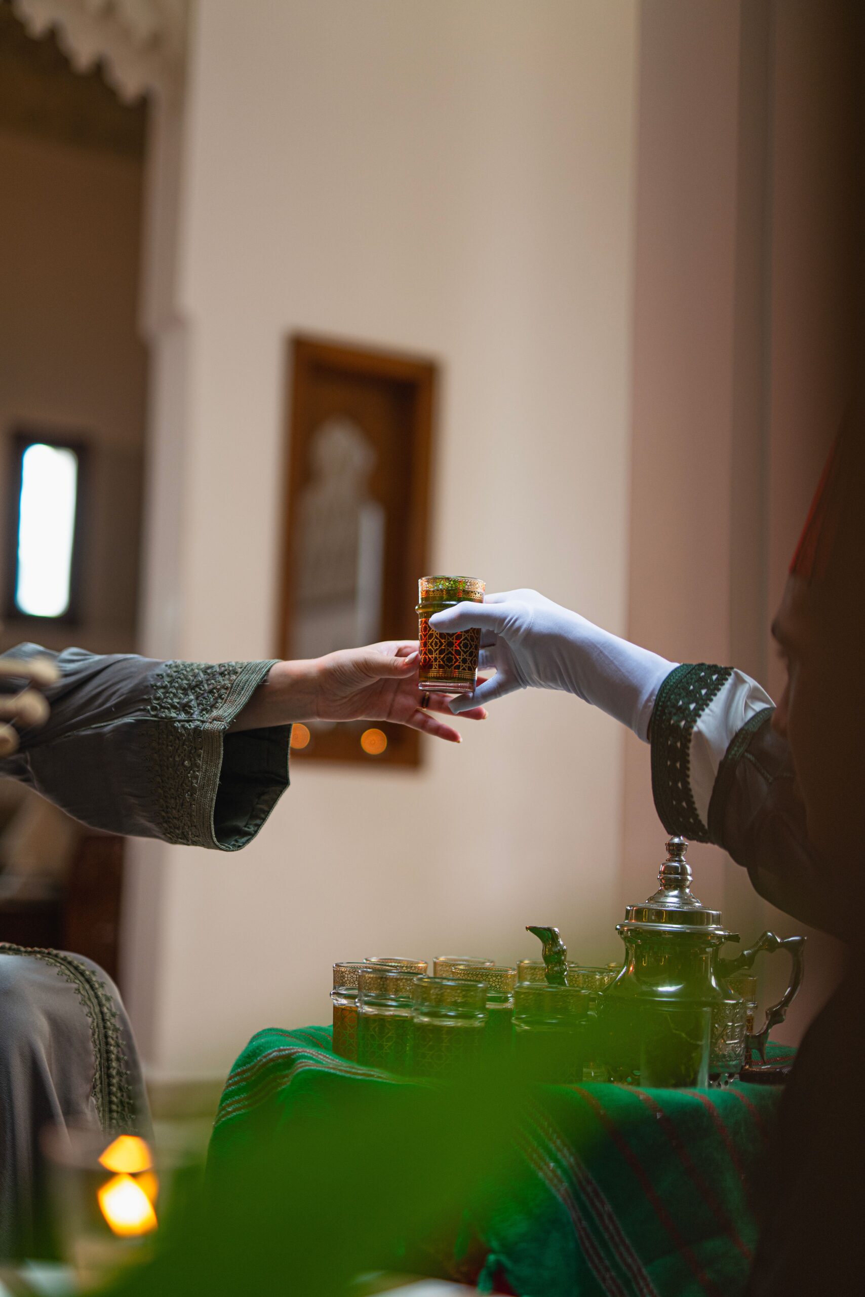 Mains échangeant un verre de thé marocain traditionnel dans un geste d'hospitalité