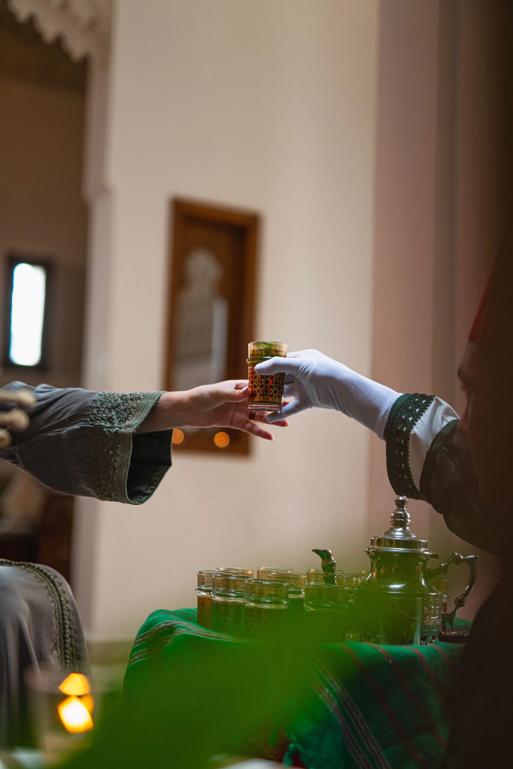 Mains échangeant un verre de thé marocain traditionnel dans un geste d'hospitalité