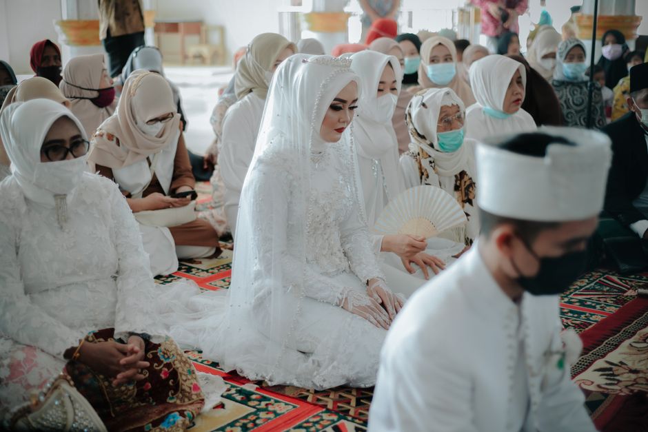 Muslim bride in a hijab at a traditional wedding ceremony surrounded by her family and witnesses