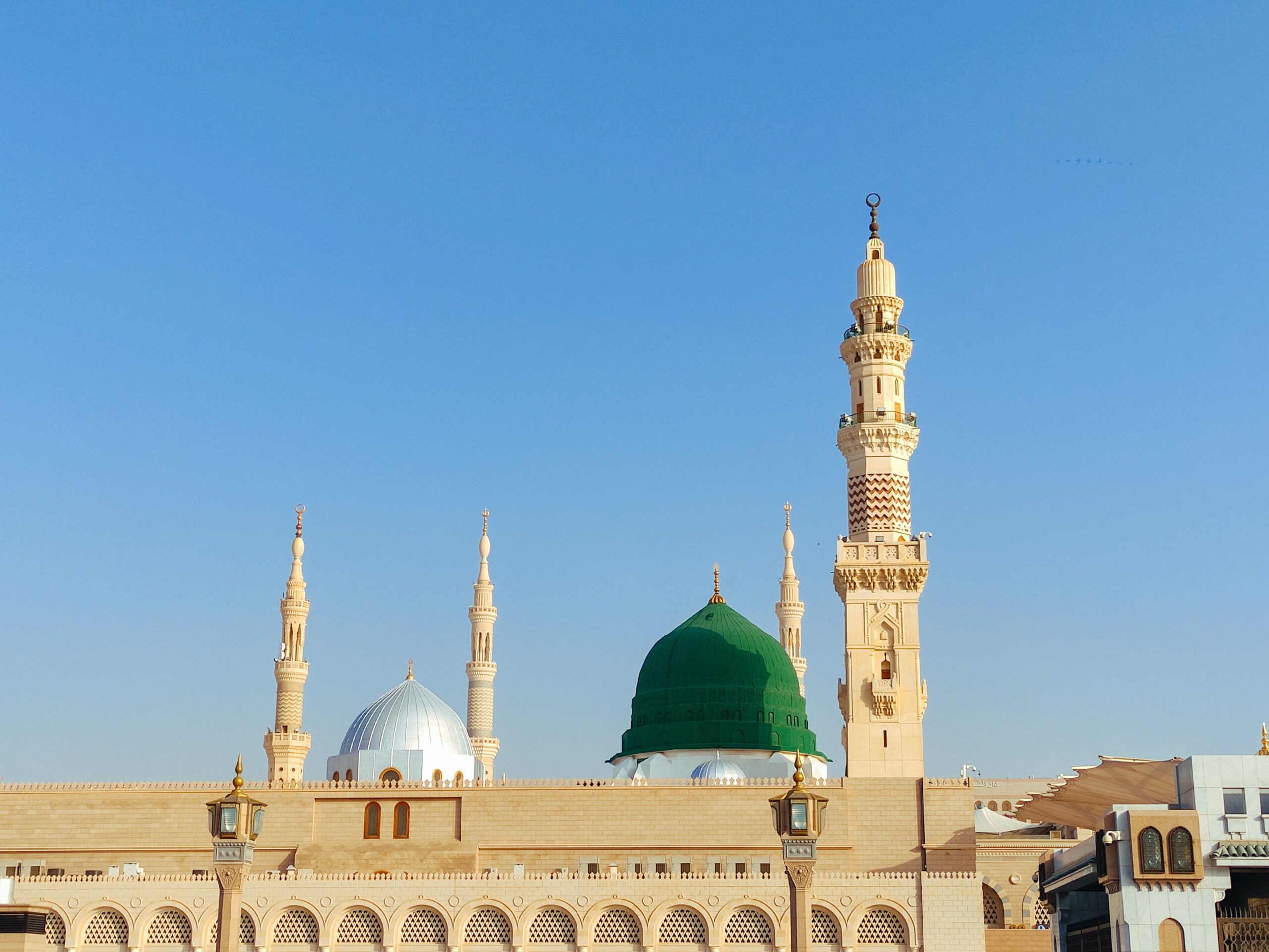 Mosquée du Prophète à Médine avec son dôme vert emblématique et ses minarets sous un ciel bleu