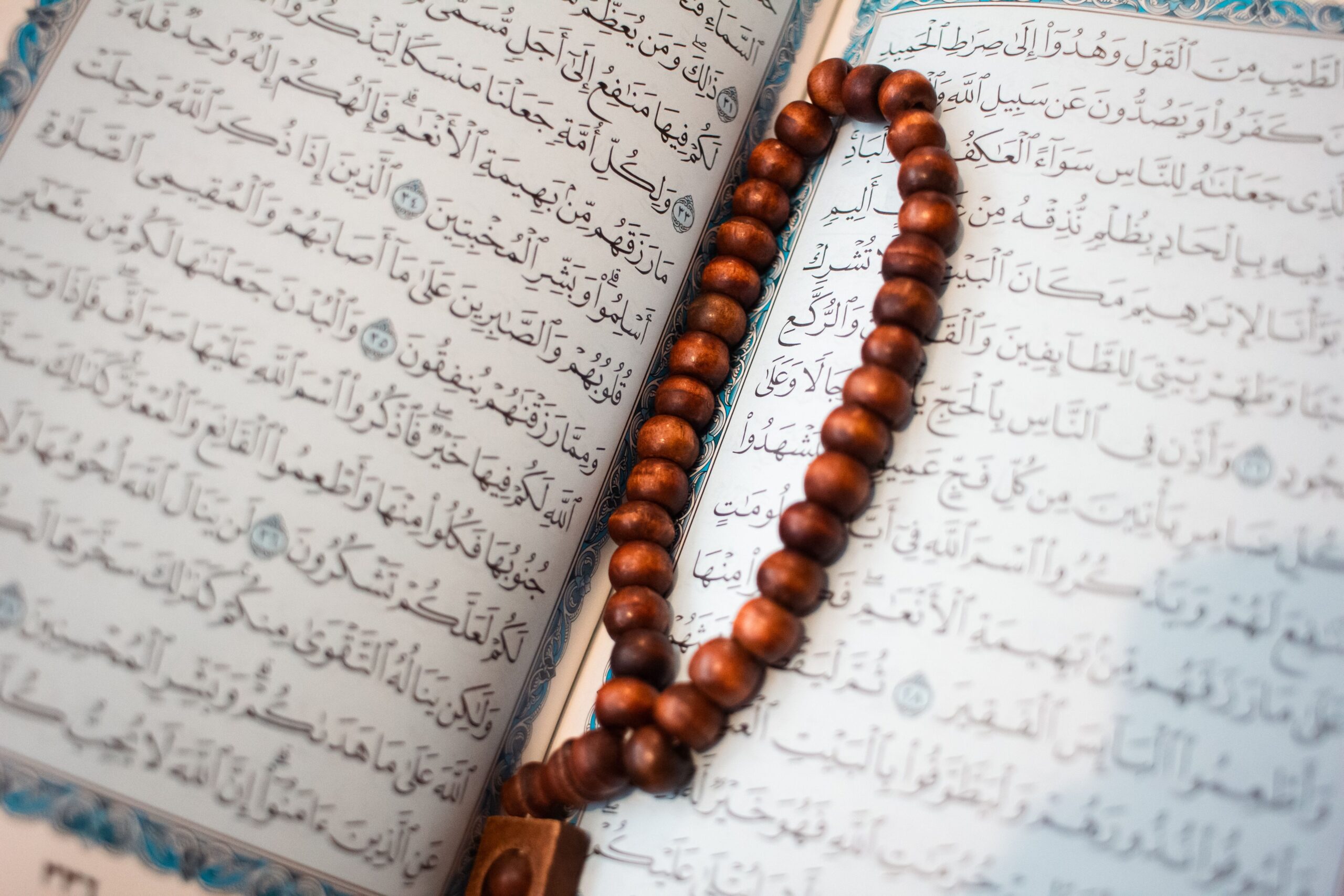 Page du Coran ouverte avec chapelet en bois sur la calligraphie arabe
