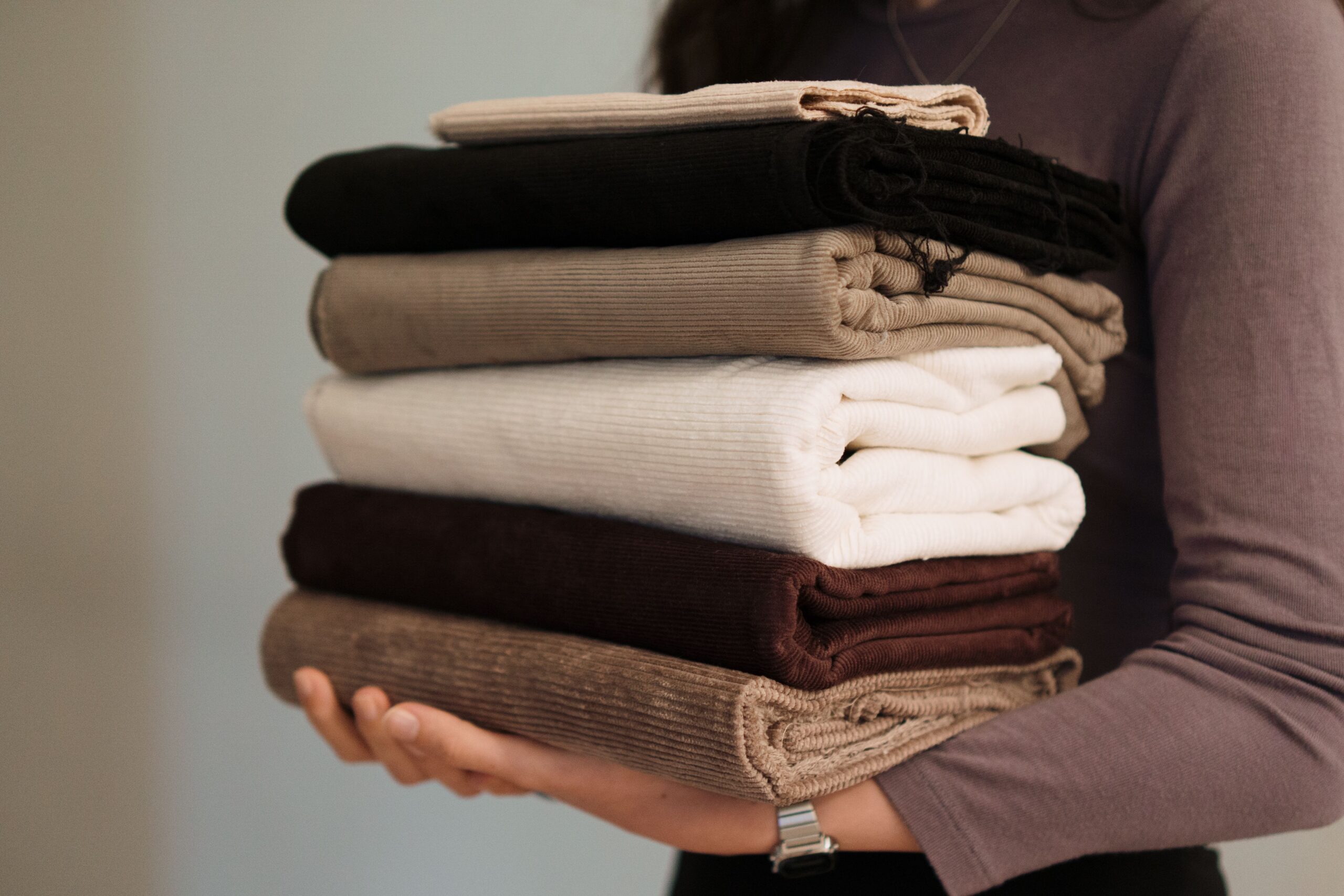 Pile de tissus dans des tons neutres : noir, beige, blanc et marron