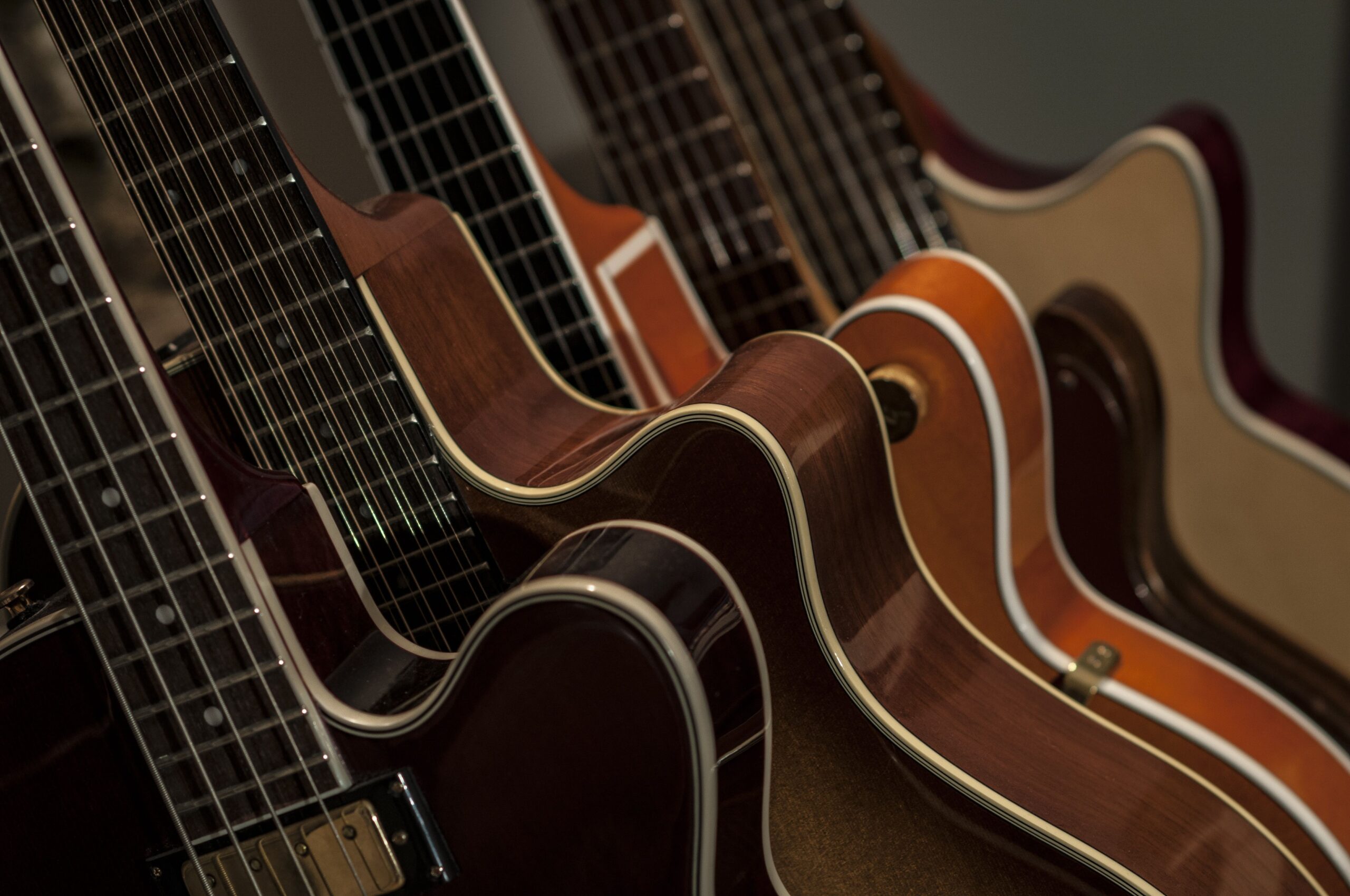 Row of lined-up acoustic guitars showing the strings and natural wood