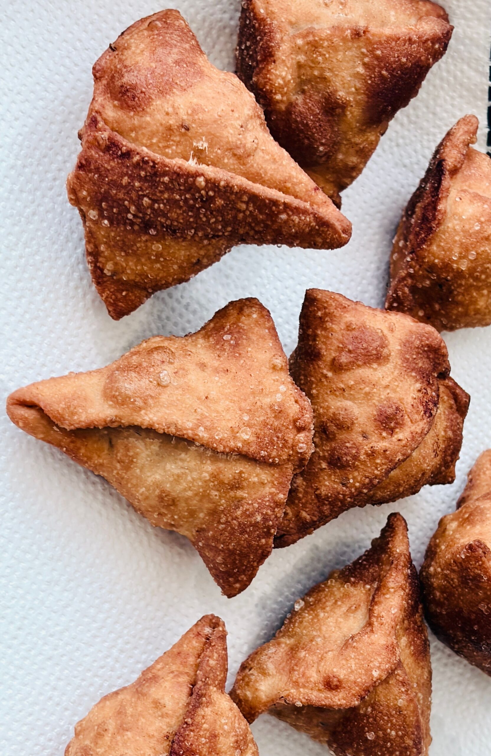 Freshly fried golden samosas on paper towels, a crispy starter typical of Ramadan