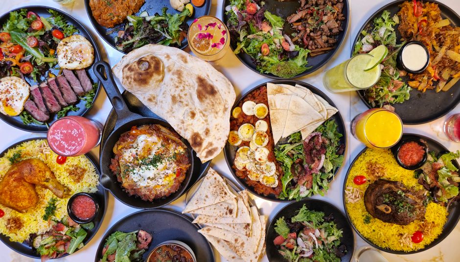 Table garnie de plats variés du Moyen-Orient avec salades fraîches, pain pita et viandes grillées