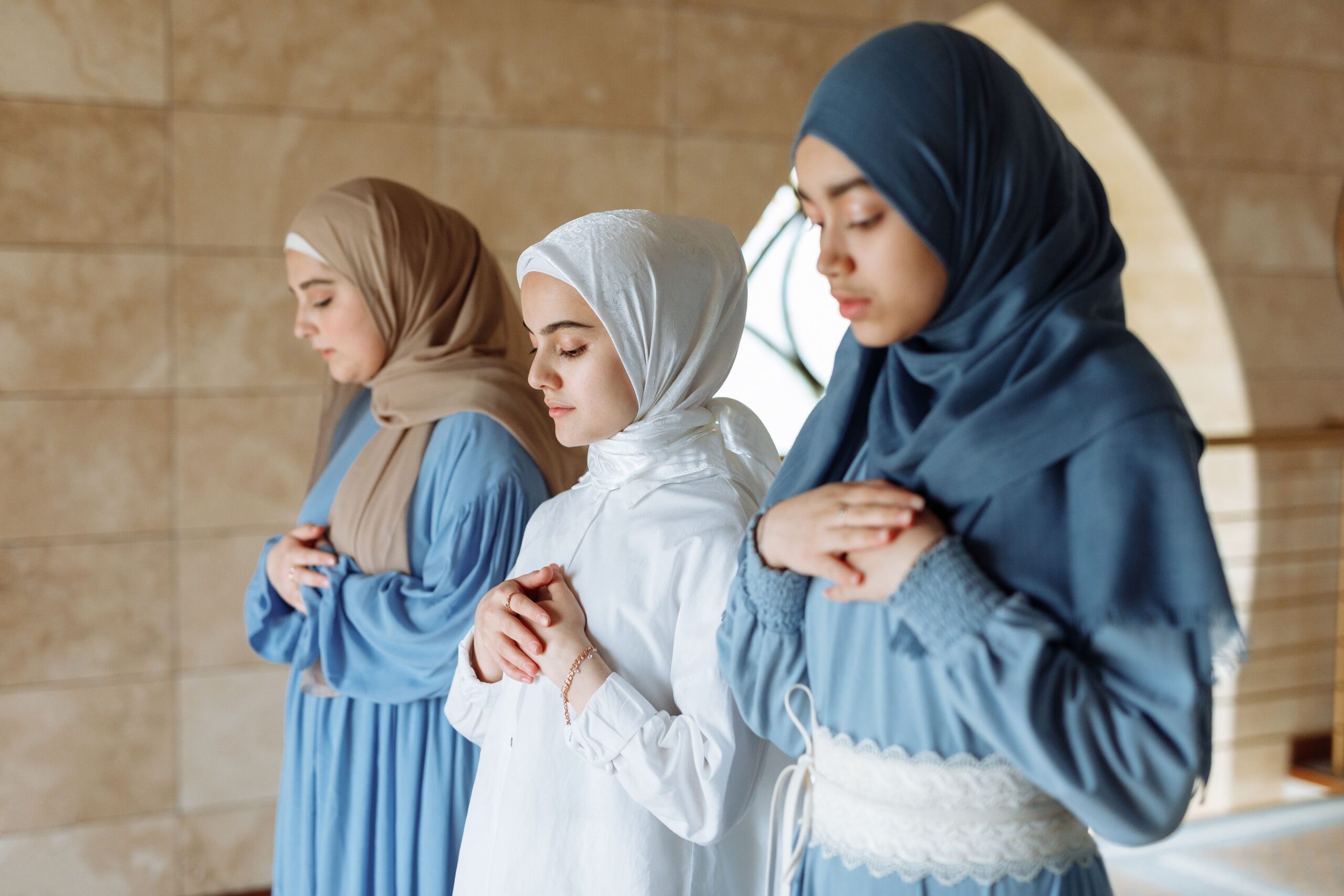 Three Muslim women wearing the hijab praying inside a mosque