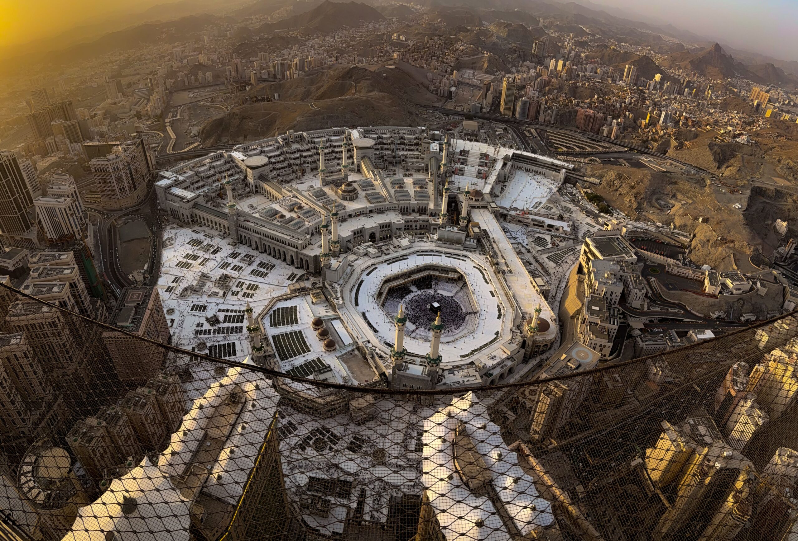Vue aérienne panoramique de La Mecque au coucher du soleil avec la Grande Mosquée et la Kaaba entourées de montagnes désertiques en Arabie saoudite