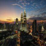 Vue panoramique de Kuala Lumpur au crépuscule avec les tours Petronas illuminées dominant la skyline de la ville