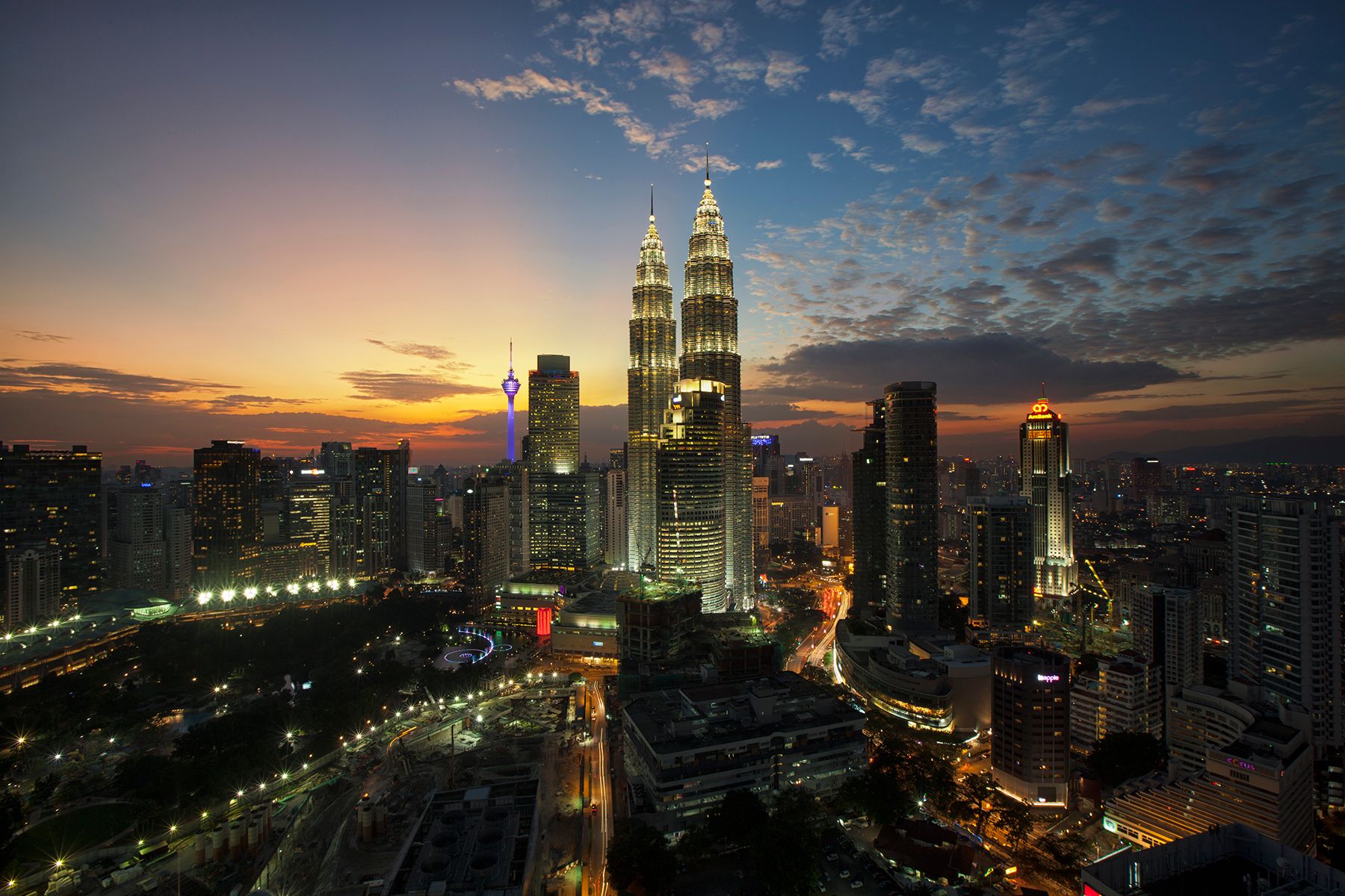 Vue panoramique de Kuala Lumpur au crépuscule avec les tours Petronas illuminées dominant la skyline de la ville